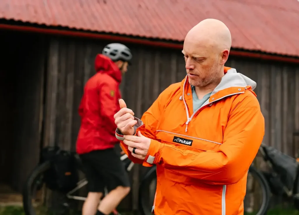 Man adjusting the cuff of an orange Páramo smock